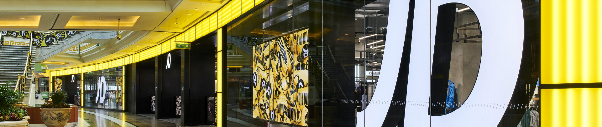 Eingangsbereich und Fassadengestaltung einer JD-Sports-Filiale mit großem JD-Logo im Einkaufszentrum