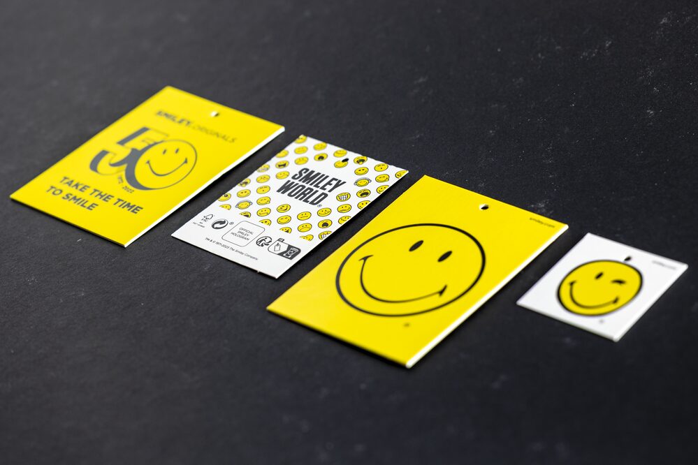 Mehrere Bekleidungsetiketten mit gelbem Smiley-World-Motiv