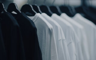 Zwarte en witte T-shirts op hangers in een kledingwinkel, illustratie van voorraadbeheer en slimme RFID-technologie in retail.